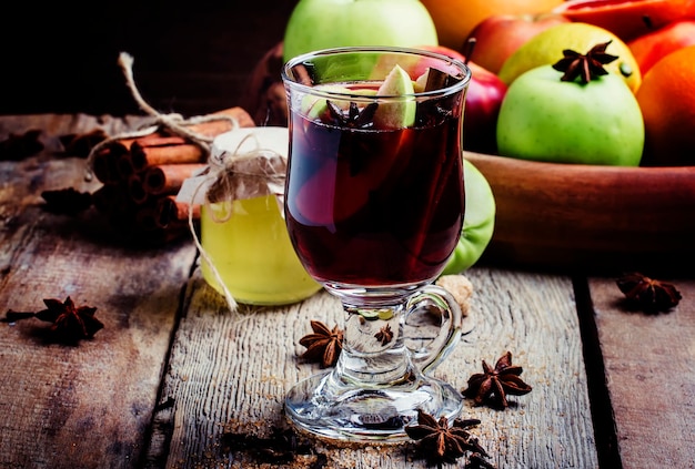 Apple and vanilla hot mulled wine with honey anise cinnamon cloves zest in a glass vintage wooden background selective focus