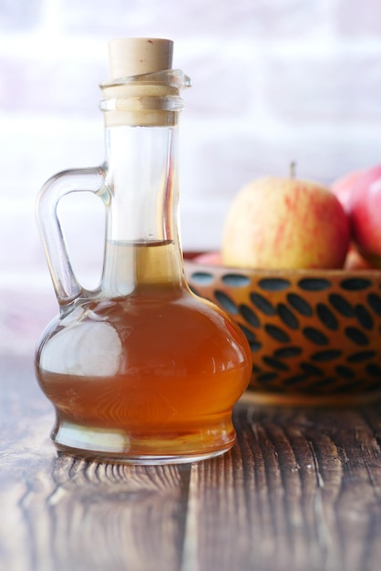 Apple vinegar in glass bottle with fresh green apple on table