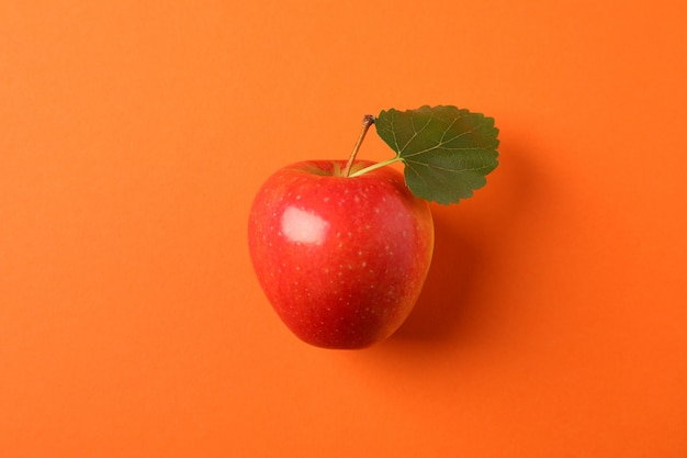 Apple with leaf on orange table