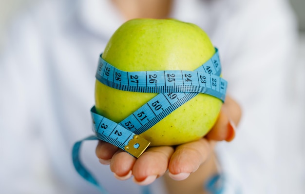 Apple with measuring tape on hand background Weight loss counting calories and healthy eating concept calculate daily nutrition intake Copy space