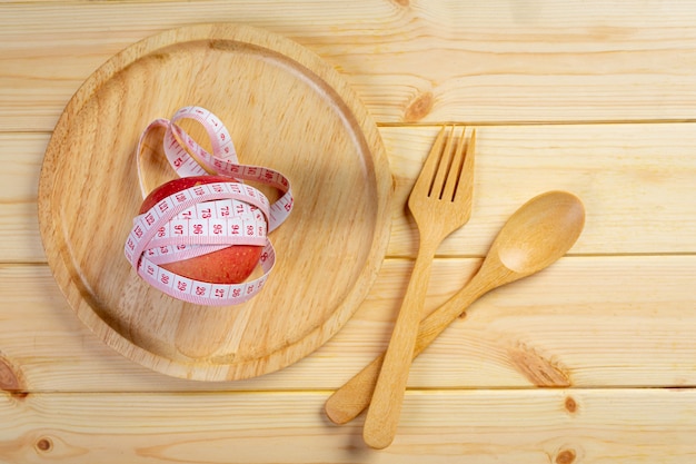 Apple with measuring tape on the wooden surface.