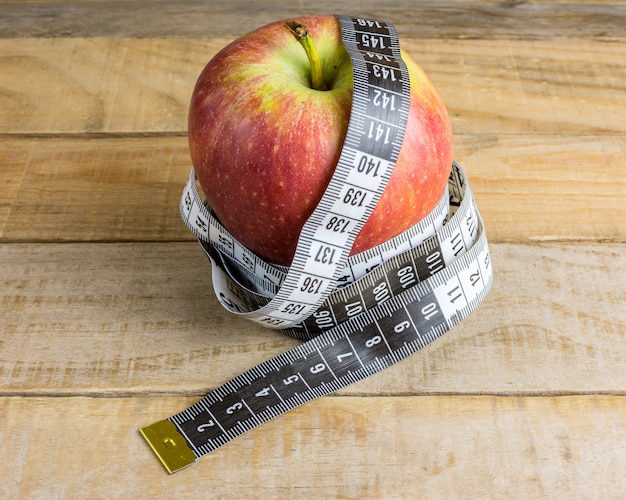 Apple with measuring tape on wooden table