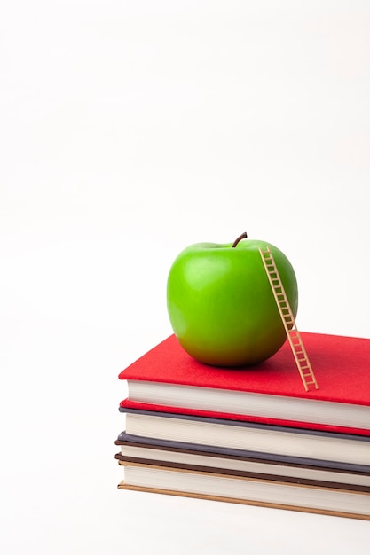 a apple and wooden ladder on stack of new books