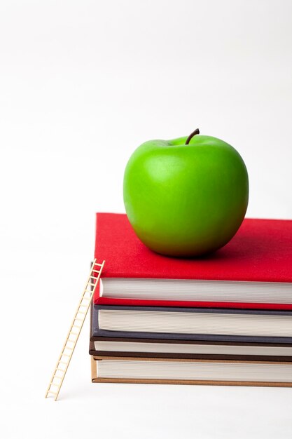 a apple and wooden ladder on stack of new books