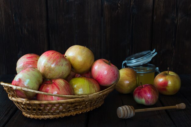 Apples in a basket and honey on a black background