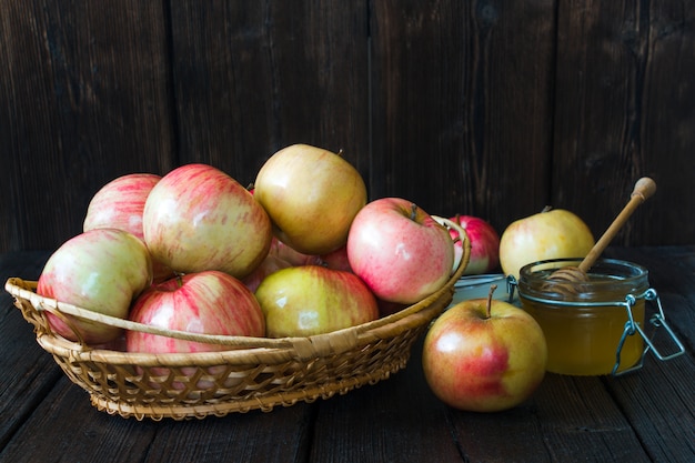 Apples in a basket and honey on a black background