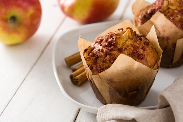 Apples and cinnamon muffins on white wooden table