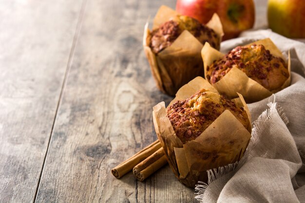 Apples and cinnamon muffins on wooden table. Copy space