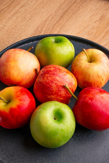 apples in a dark plate on a wooden table