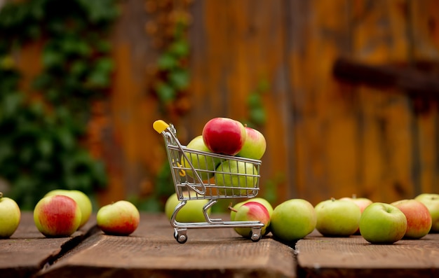 Apples in little cart on wooden desk in a garden