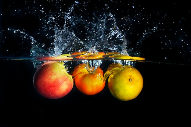 Apples and orange splashing into blue clear water splash 