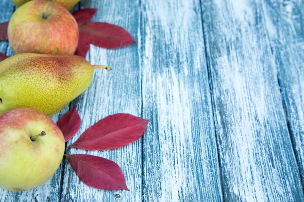 Photo apples, pears and autumn leaves on wooden background. autumn background