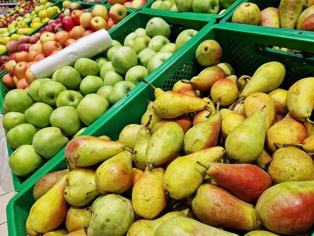 Apples and pears in plastic boxes in a store closeup ripe apples for sale side view selling fruits