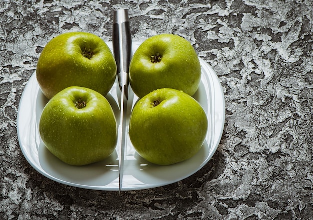 Яблоки в тарелке на сером фоне