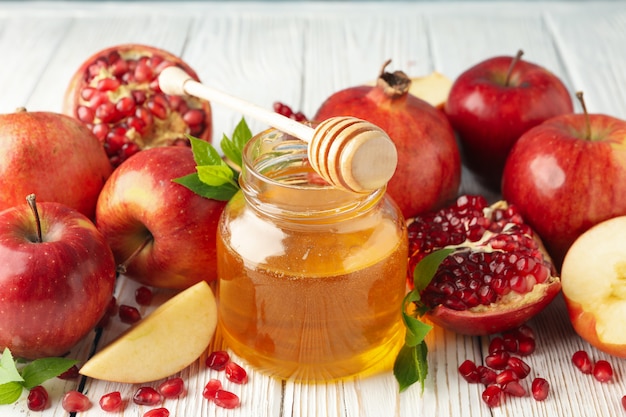 Apples, pomegranate and honey on wooden, close up