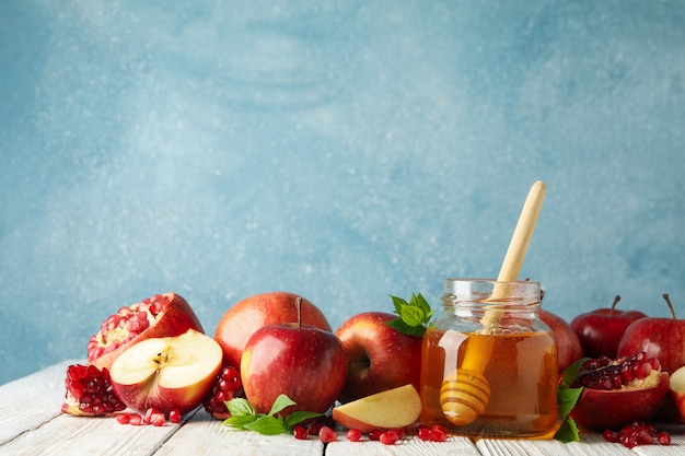 Apples, pomegranate and honey on wooden table, space for text