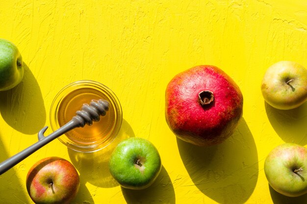 Photo apples with honey pomegranate on a yellow table for the jewish new year horizontal