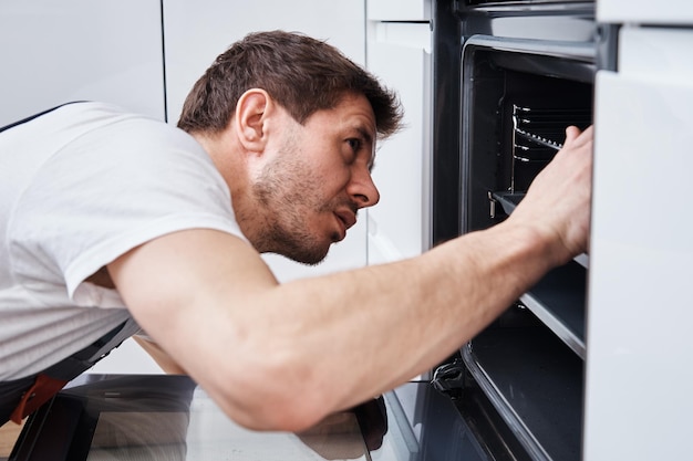 Appliance maintenance man fixing problem in the oven in kitchen