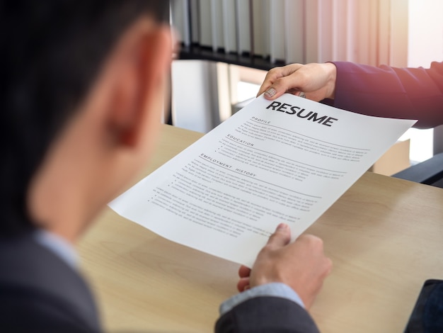 Applicant's hand in suit giving resume to employer for review the profile