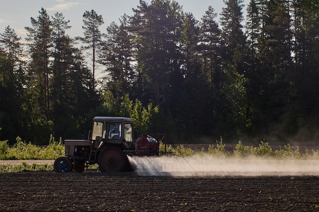 Foto applicazione di fertilizzanti chimici alle colture mediante spruzzatura effettuata da un trattore agricolo con spruzzatore incorporato