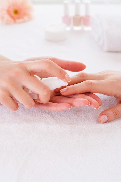 Applying antiseptic on nails. Close-up of manicure master spraying antiseptic on female finger