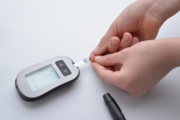 Foto applicazione del sangue dal dito alla striscia e al dispositivo per la misurazione dei livelli di glucosio nel sangue concetto di monitoraggio della salute e gestione del diabete