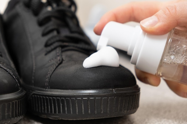 Applying cleaning foam from a bottle to nubuck men's shoes