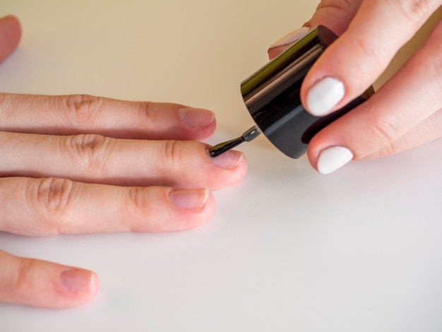 Applying a colorless base to the nail. Manicure at home