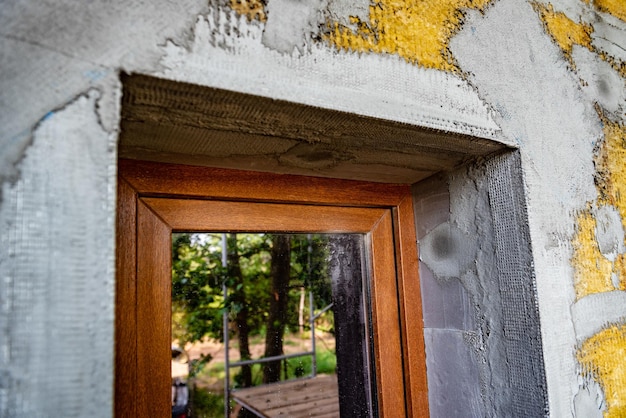 Applying construction glue layer on insulated wall for covering fiberglass reinforcing mesh on mineral wool.