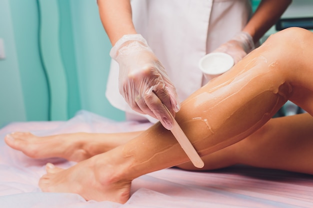 Applying a contact gel before the procedure of laser hair removal. Application of sugar paste for the procedure of shugaring.