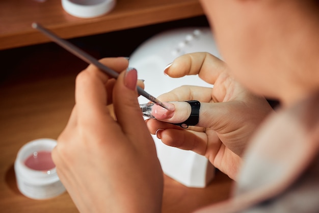 Applying gel nail Polish, the woman doing the manicure.