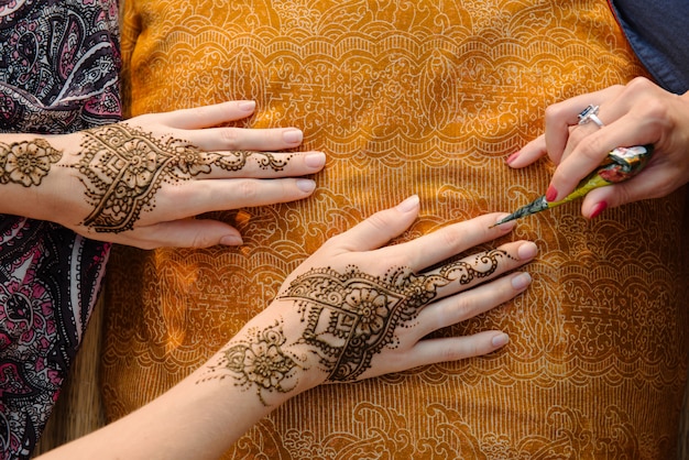 Applying henna tattoo on women hands