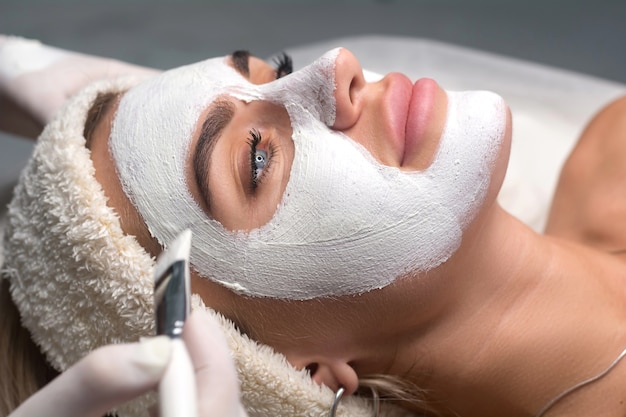 Applying a mask to the face in a beauty salon. Cosmetologist and procedure for rejuvenation