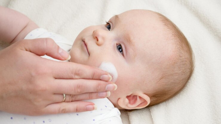 皮膚炎に悩む赤ちゃんの肌に保湿クリームを塗る 生まれたばかりの赤ちゃんの健康の概念