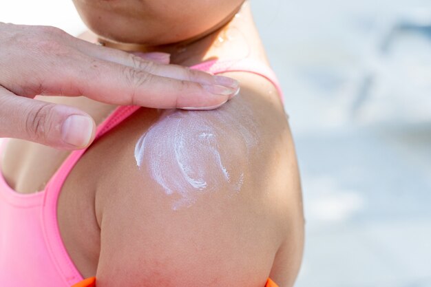 小さな子供の顔に日焼け止めクリームを塗る、太陽と紫外線から保護