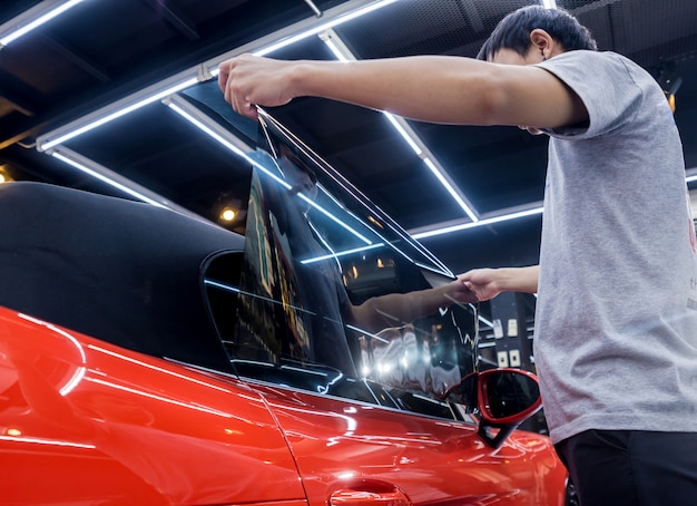 Applying tinting foil on a car window in a auto service