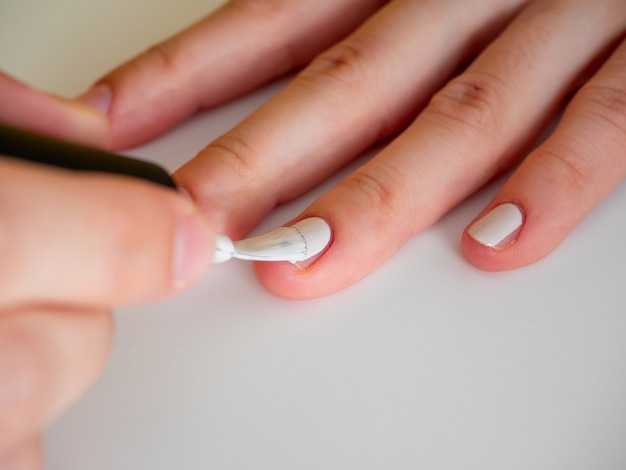 Applying white nail polish to the nail. Manicure and nail care concept