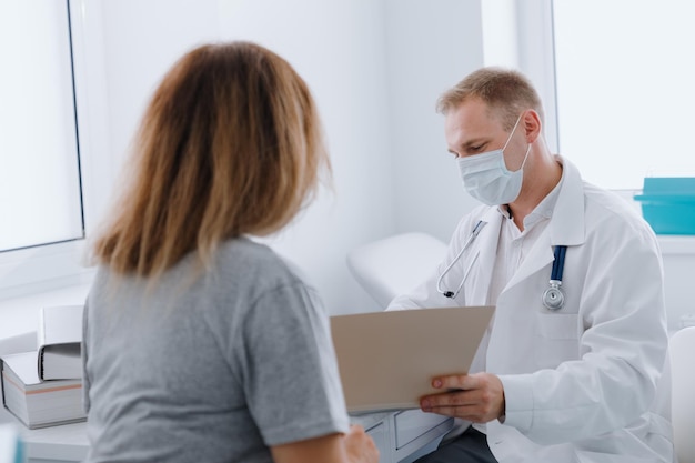 An appointment with a therapist A male doctor studies a young woman's medical record in his office