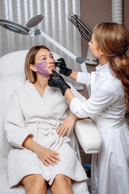 An approximate image of the face of a young girl with purple tapes on her face receiving a smoothing massage