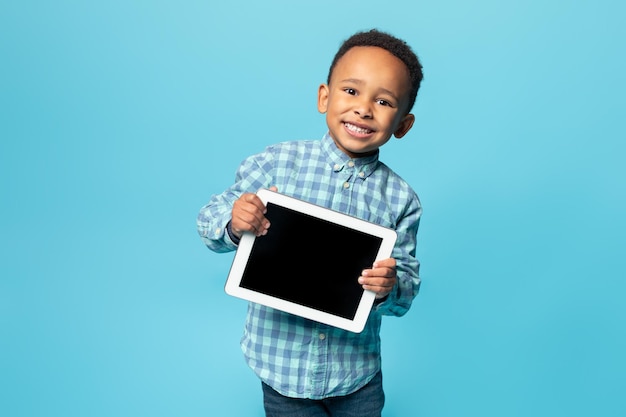 Apps and distance learning for kids happy african american boy showing tablet with blank screen mockup