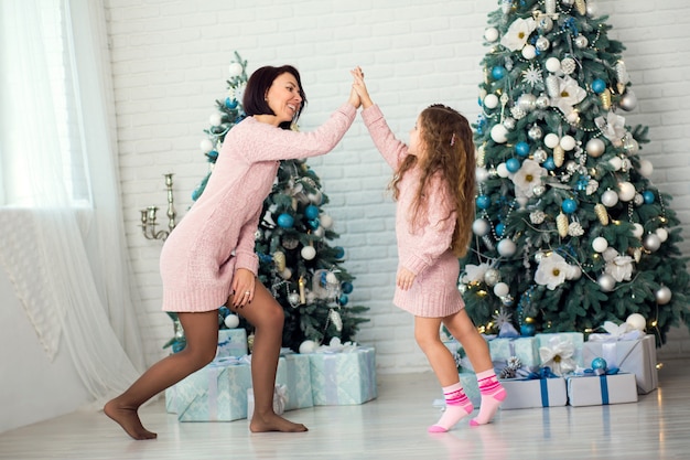 Appy familiemoeder en kinddochter op Kerstmisochtend bij de Kerstboom met giften.