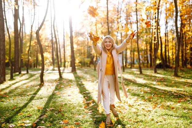 Foto appy jonge vrouw die plezier heeft met bladeren in het herfstpark