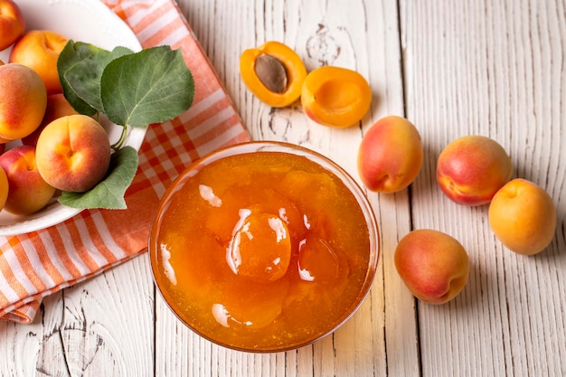 Apricot fruits and apricot jam on the wooden background