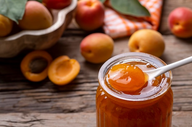 Apricot fruits and apricot jam on the wooden background