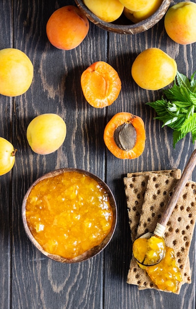 Apricot jam in a wooden bowl and fresh apricots