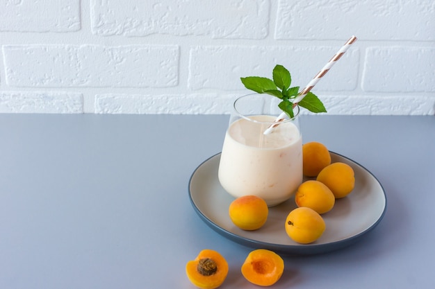 Apricot smoothie or yogurt and ripe apricots on a table. Delicious milk drink with ripe apricots.