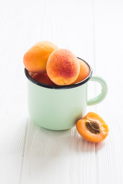 Apricot in tea cup on a white wooden table