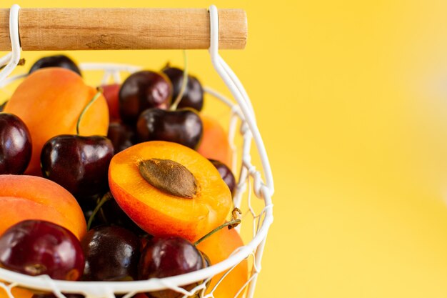 Apricots and cherries in white metal basket