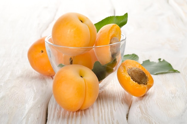 Photo apricots in a cup on a wooden background