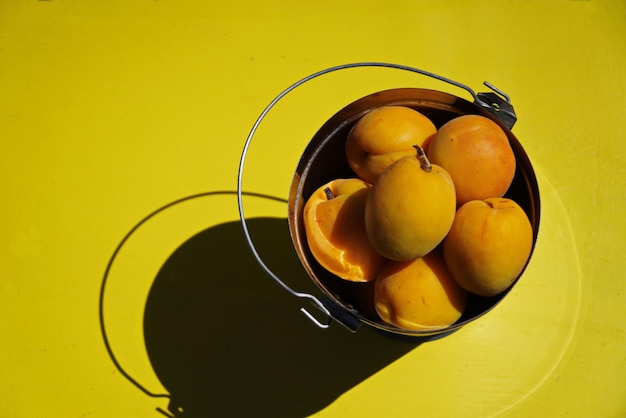 Apricots in a decorative bucket on a yellow chair
